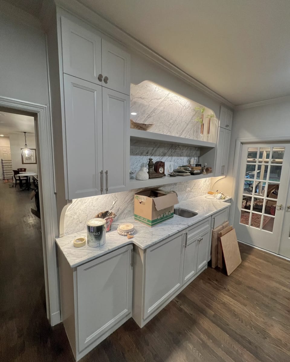 White painted cabinetry and open shelving above a stone counter