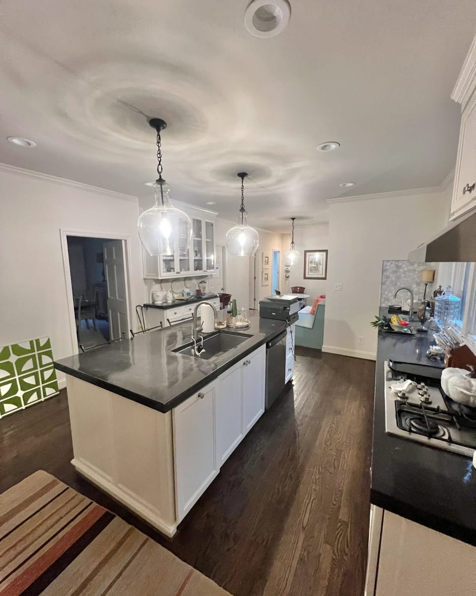 Kitchen island and painted cabinetry under pendant lights