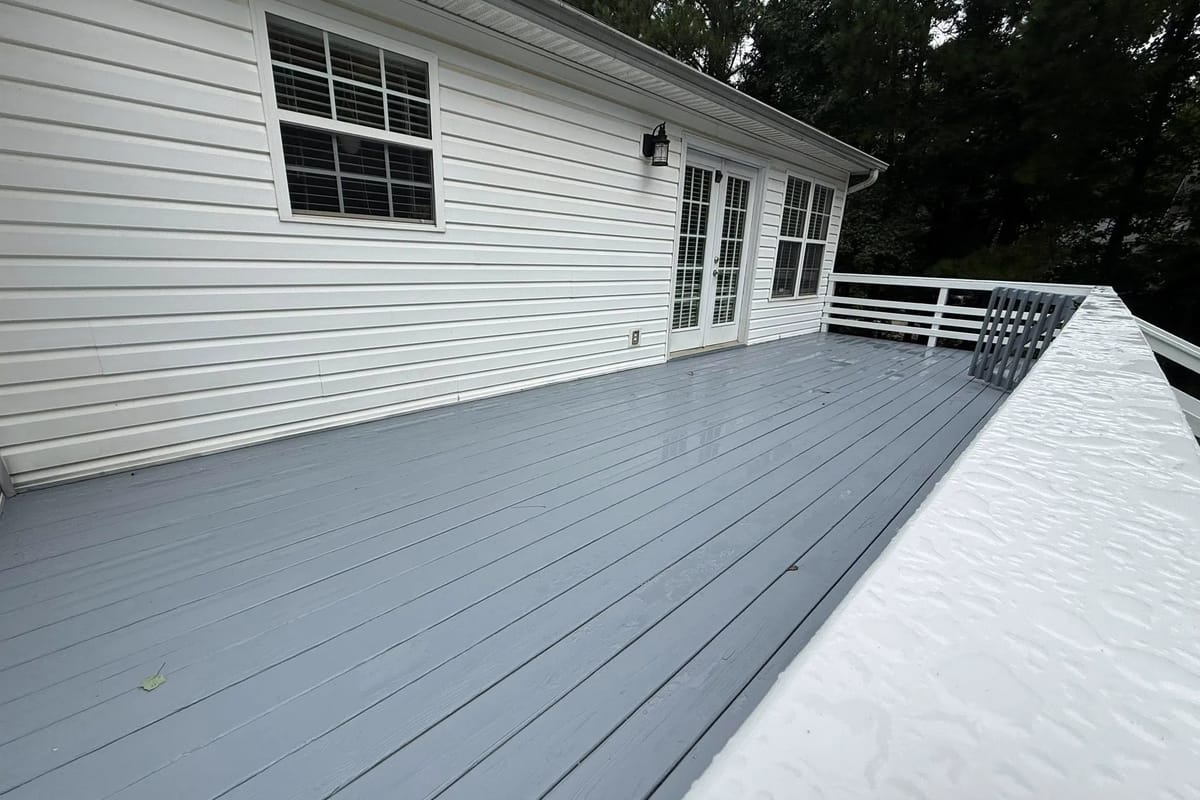 Grey painted deck boards running the length of a house clad in white lap siding