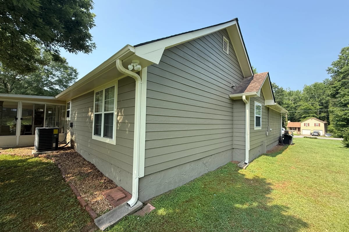 Sage green lap siding with white trim, window surrounds and downspouts