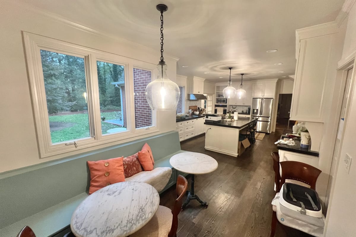 Open kitchen and breakfast area with painted white walls, ceiling and window trim