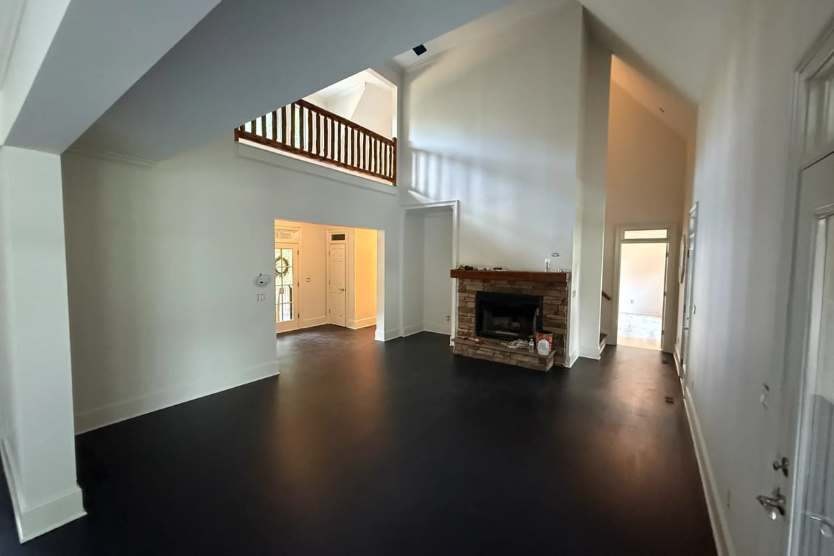 Empty living room with freshly painted white walls and trim under a two-storey ceiling